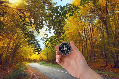 Image of Woman holding compass near road going through forest in autumn, closeup