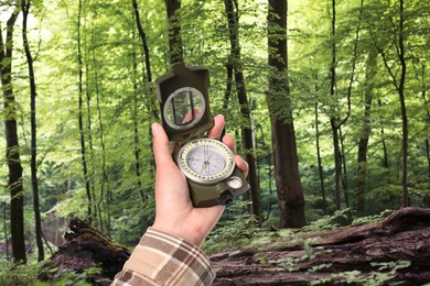 Image of Woman holding compass in lush forest, closeup