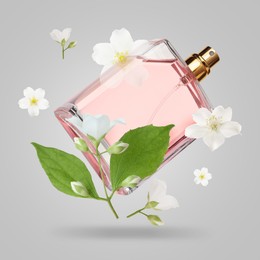 Image of Bottle of floral perfume and jasmine flowers in air on light grey background