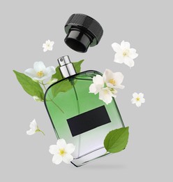 Image of Bottle of floral perfume and jasmine flowers in air on light grey background