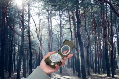 Image of Woman holding compass in sunlit forest, closeup