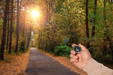 Image of Man holding compass on pathway in autumn forest, closeup