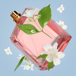 Bottle of floral perfume and jasmine flowers in air on light blue background