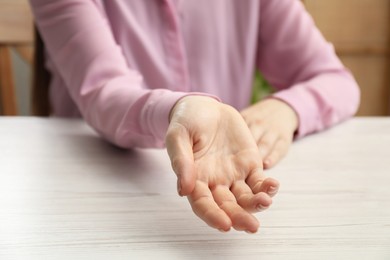 Photo of Woman showing palm at white wooden table, closeup. Chiromancy and foretelling