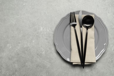 Photo of Stylish cutlery, napkin and plate on grey table, top view. Space for text