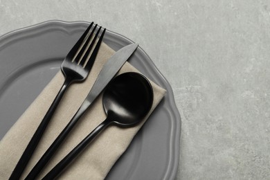 Photo of Stylish cutlery, napkin and plate on grey table, top view. Space for text