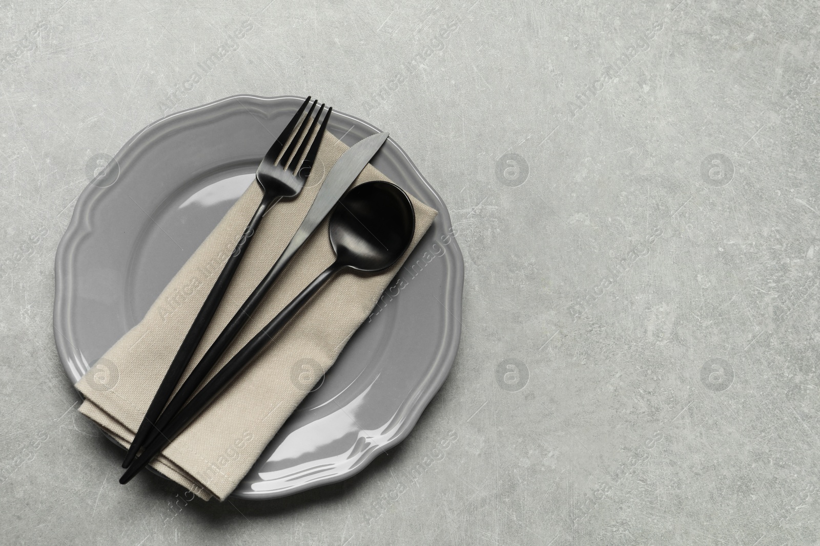 Photo of Stylish cutlery, napkin and plate on grey table, top view. Space for text