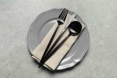 Photo of Stylish cutlery, napkin and plate on grey table, top view