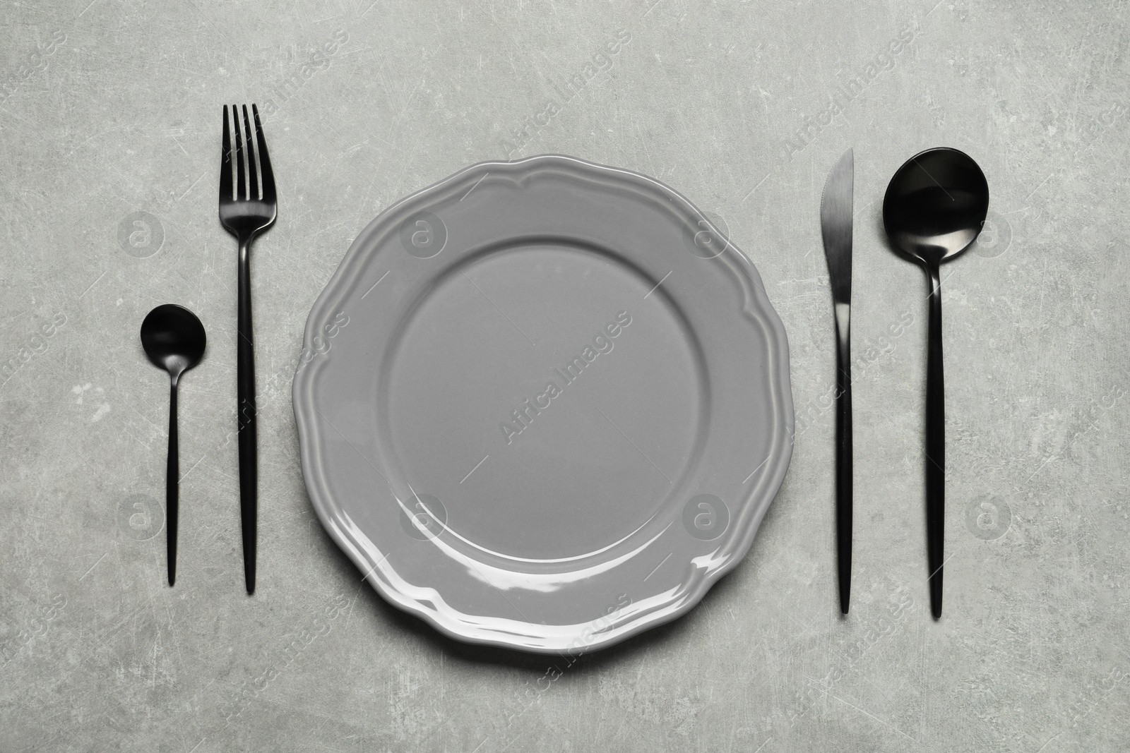 Photo of Stylish cutlery and plate on grey table, flat lay