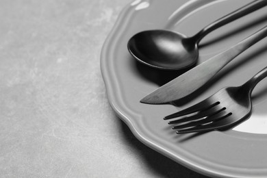 Photo of Stylish cutlery and plate on grey table, closeup. Space for text