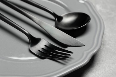 Photo of Stylish cutlery and plate on grey table, closeup