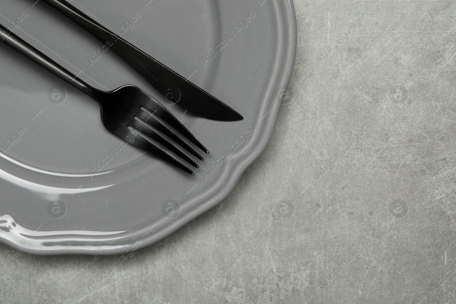 Photo of Stylish cutlery and plate on grey table, top view. Space for text