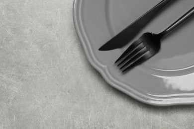 Photo of Stylish cutlery and plate on grey table, top view. Space for text