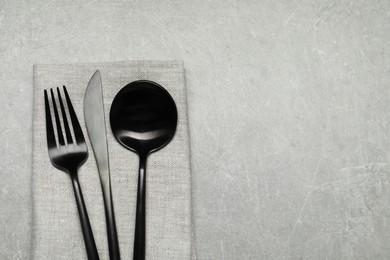 Photo of Stylish cutlery and napkin on grey table, top view. Space for text