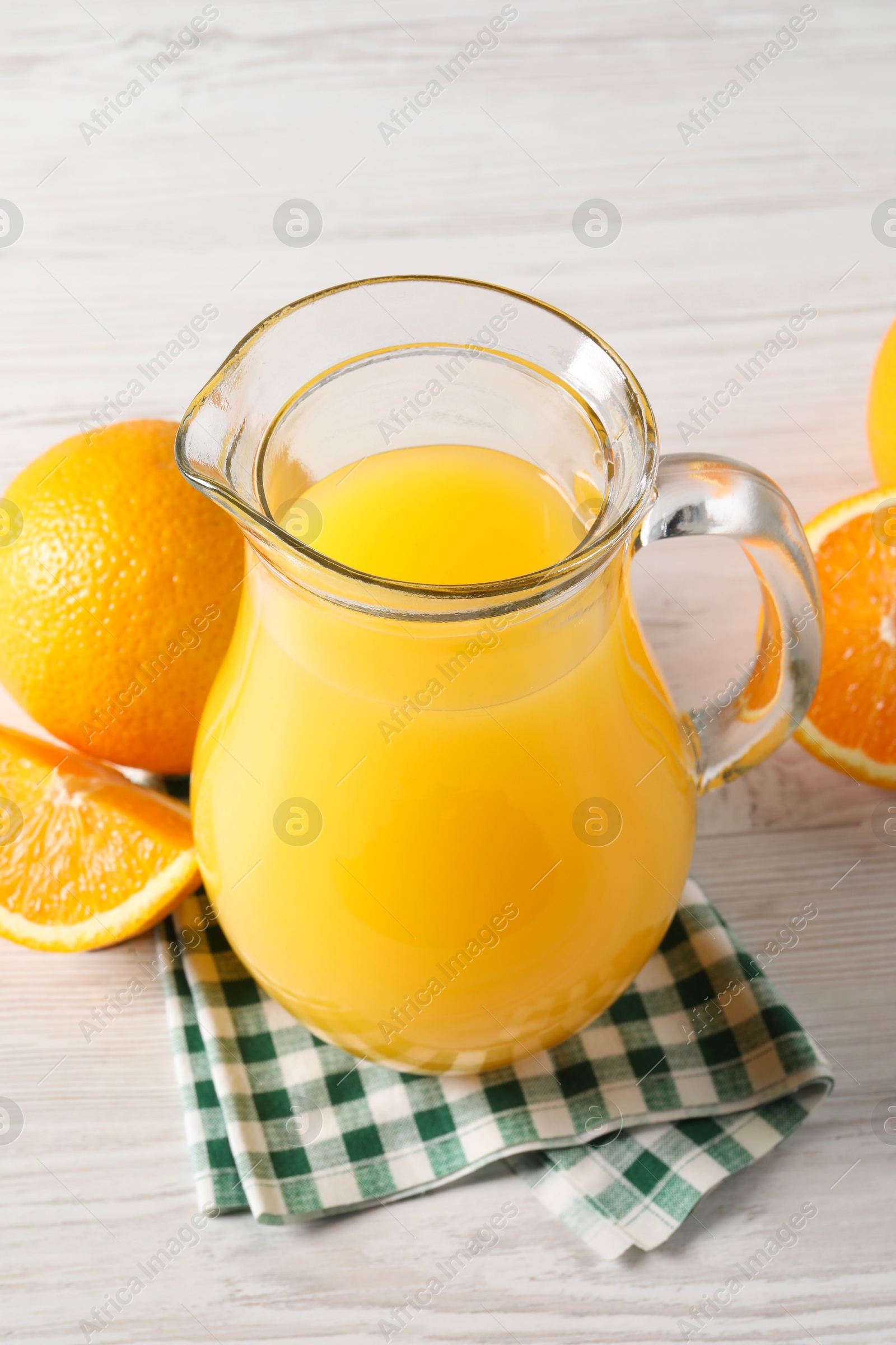 Photo of Tasty orange juice in glass jug and fresh fruits on white wooden table