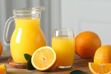 Tasty orange juice, green leaves and fresh fruits on wooden table