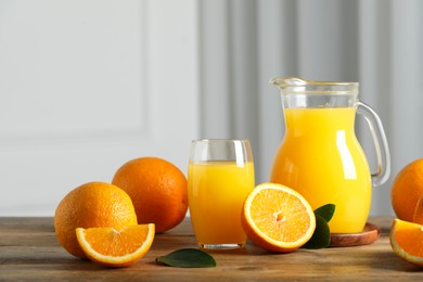 Photo of Tasty orange juice, green leaves and fresh fruits on wooden table