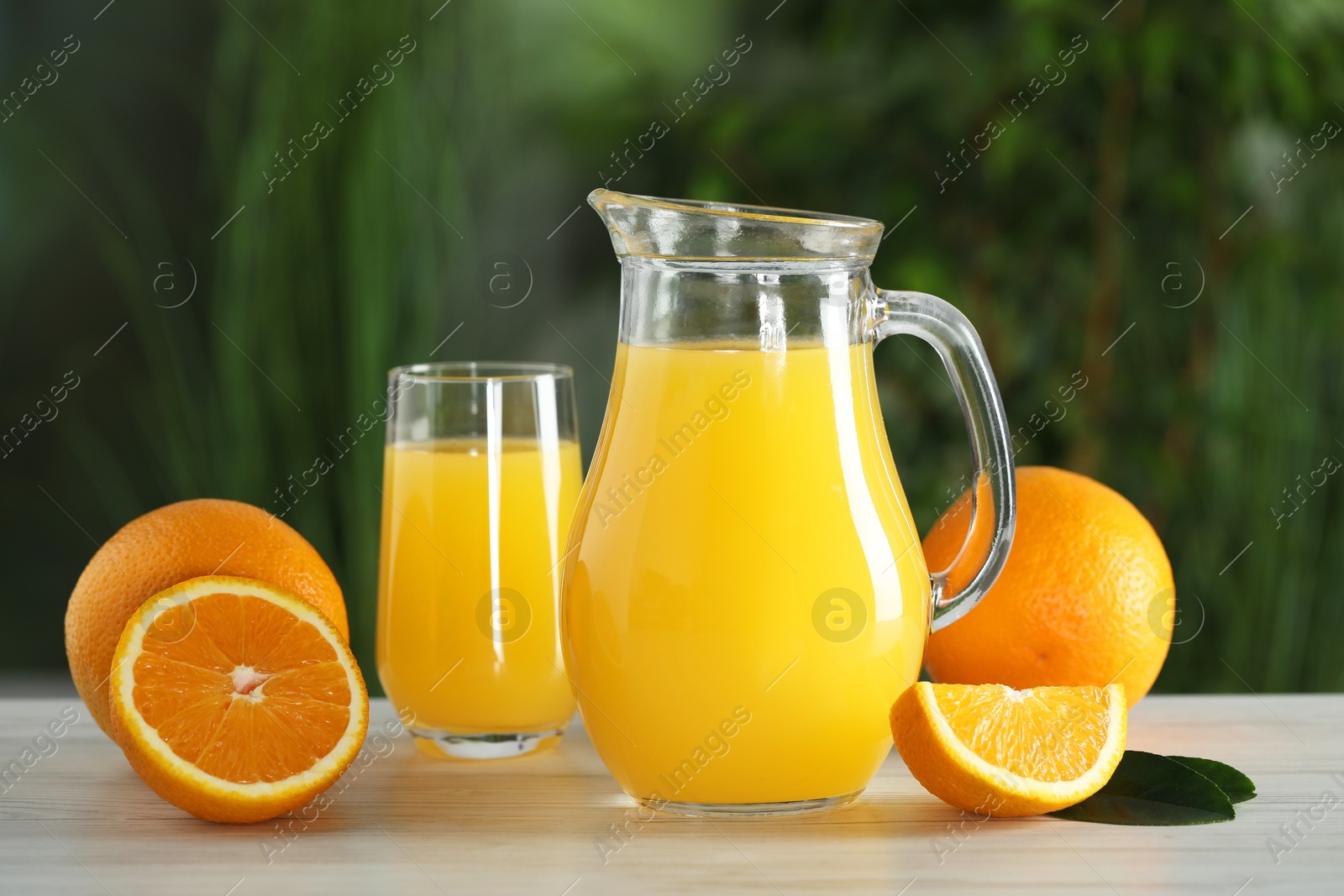 Photo of Tasty orange juice and fresh fruits on white wooden table outdoors