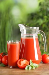 Photo of Tasty tomato juice, basil and fresh vegetables on wooden table outdoors