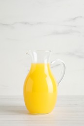 Photo of Fresh orange juice in glass jug on white wooden table