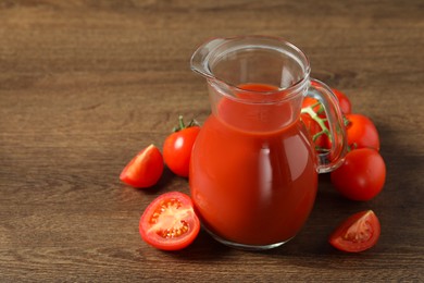 Tasty tomato juice in jug and vegetables on wooden table. Space for text