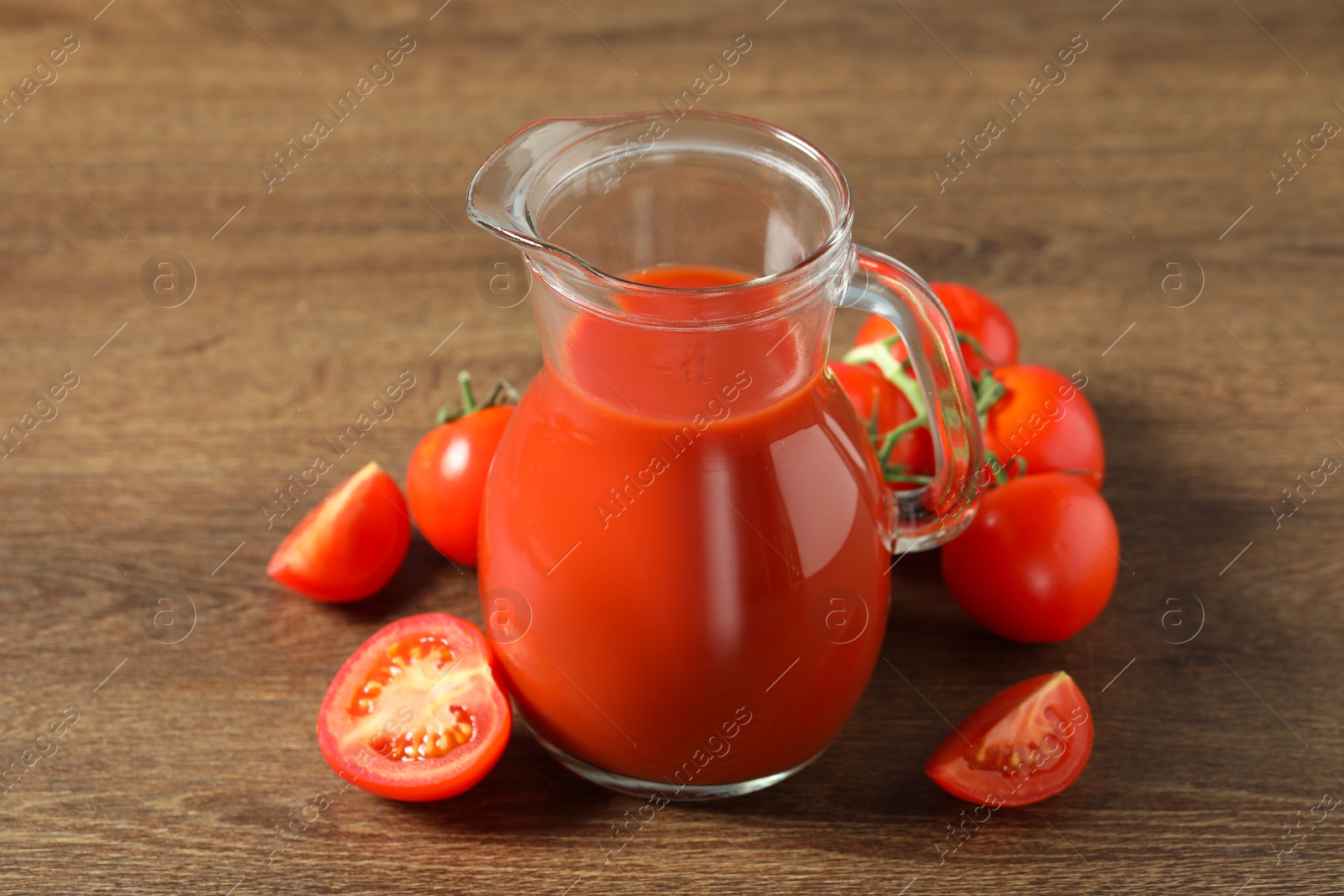 Photo of Tasty tomato juice in jug and vegetables on wooden table