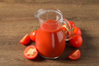 Tasty tomato juice in jug and vegetables on wooden table