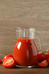 Photo of Tasty tomato juice in jug and vegetables on wooden table