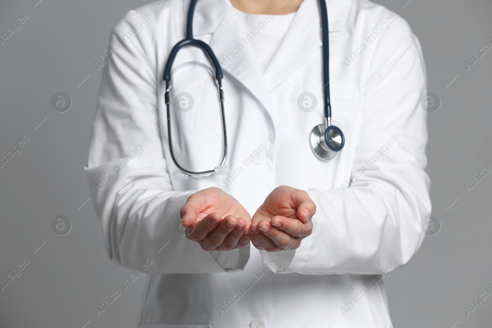 Photo of Doctor holding something on grey background, closeup