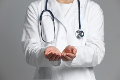 Doctor holding something on grey background, closeup