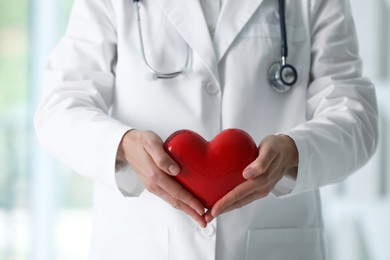 Photo of Doctor with red heart in clinic, closeup