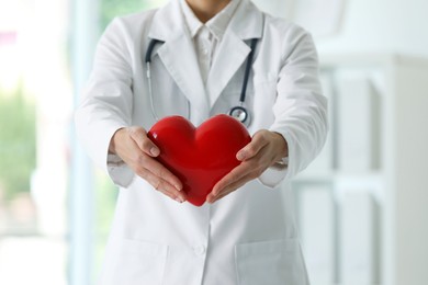 Photo of Doctor with red heart in clinic, closeup