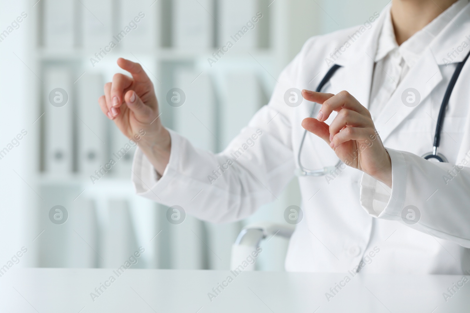 Photo of Doctor with stethoscope holding something at table in clinic, closeup