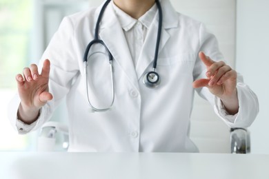 Photo of Doctor with stethoscope holding something at table in clinic, closeup