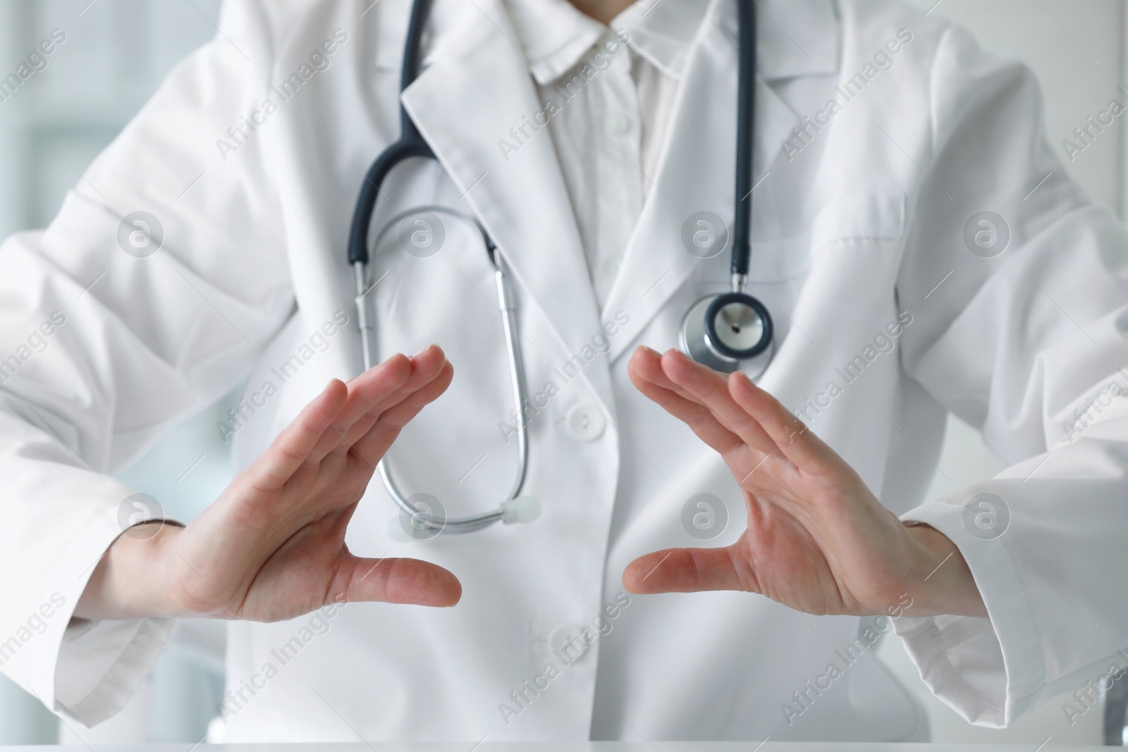 Photo of Doctor with stethoscope holding something at table in clinic, closeup