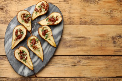 Tasty baked pears with nuts, blue cheese, thyme and honey on wooden table, top view. Space for text