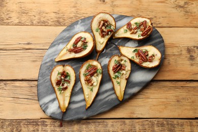 Tasty baked pears with nuts, blue cheese, thyme and honey on wooden table, top view