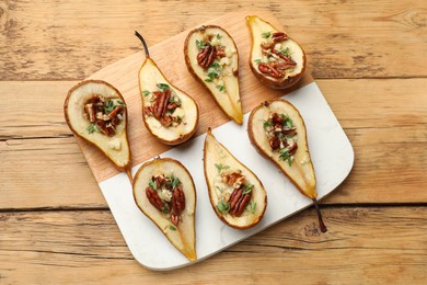 Photo of Tasty baked pears with nuts, blue cheese, thyme and honey on wooden table, top view