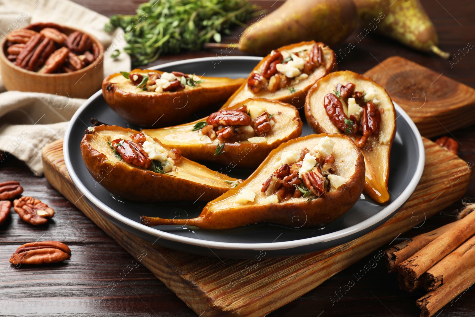 Photo of Delicious baked pears with nuts, blue cheese and honey on wooden table, closeup