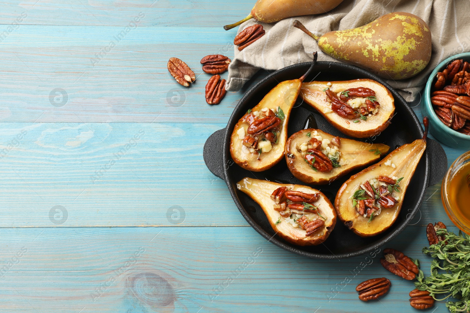 Photo of Delicious baked pears with nuts, blue cheese, thyme and honey on light blue wooden table, flat lay. Space for text