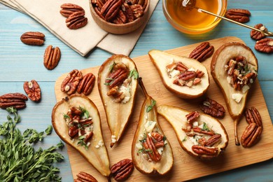 Photo of Delicious baked pears with nuts, blue cheese, thyme and honey on light blue wooden table, flat lay