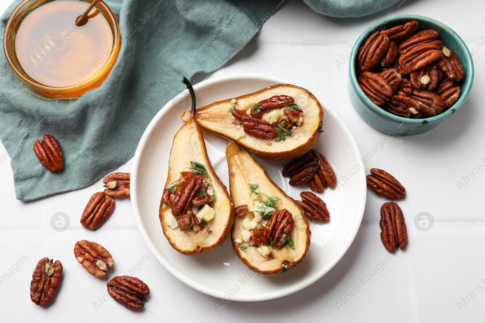 Photo of Delicious baked pears with nuts, blue cheese, thyme and honey on white tiled table, flat lay