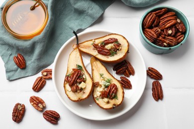 Delicious baked pears with nuts, blue cheese, thyme and honey on white tiled table, flat lay