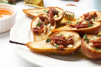 Photo of Delicious baked pears with nuts, blue cheese, thyme and honey on white table, closeup