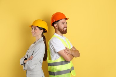 Photo of Engineers in hard hats on yellow background, space for text