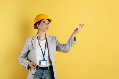 Photo of Engineer in hard hat on yellow background, space for text