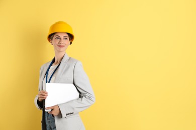 Engineer in hard hat with laptop on yellow background, space for text