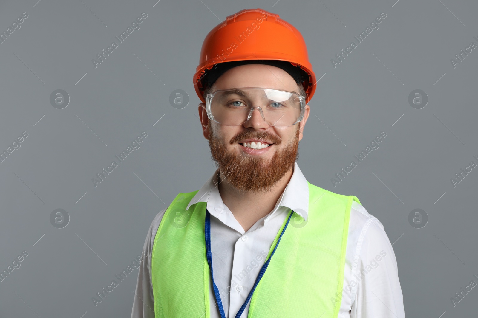 Photo of Engineer in hard hat and goggles on grey background