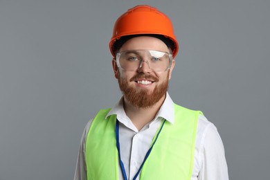 Photo of Engineer in hard hat and goggles on grey background