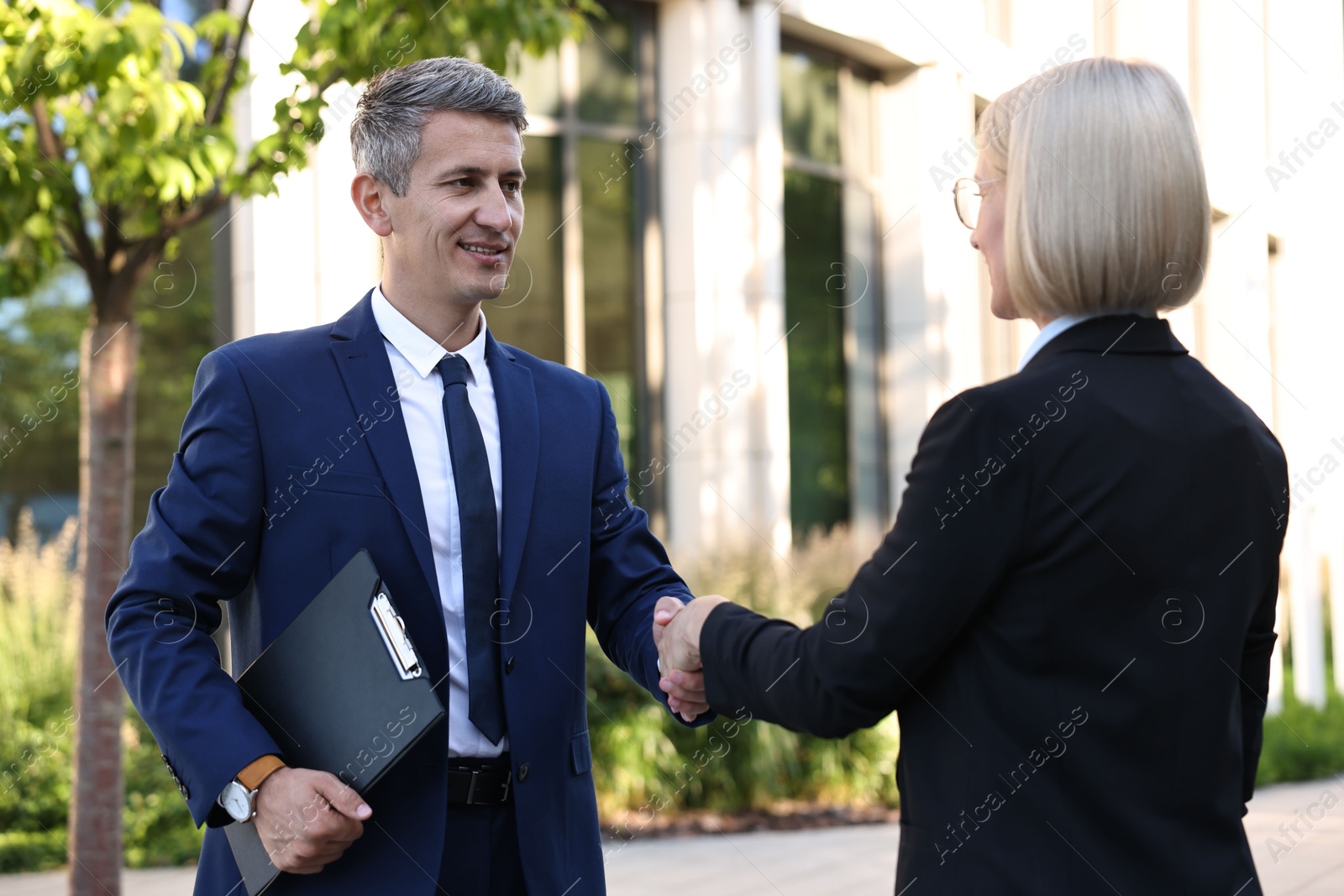 Photo of International relations. Diplomats shaking hands during meeting outdoors